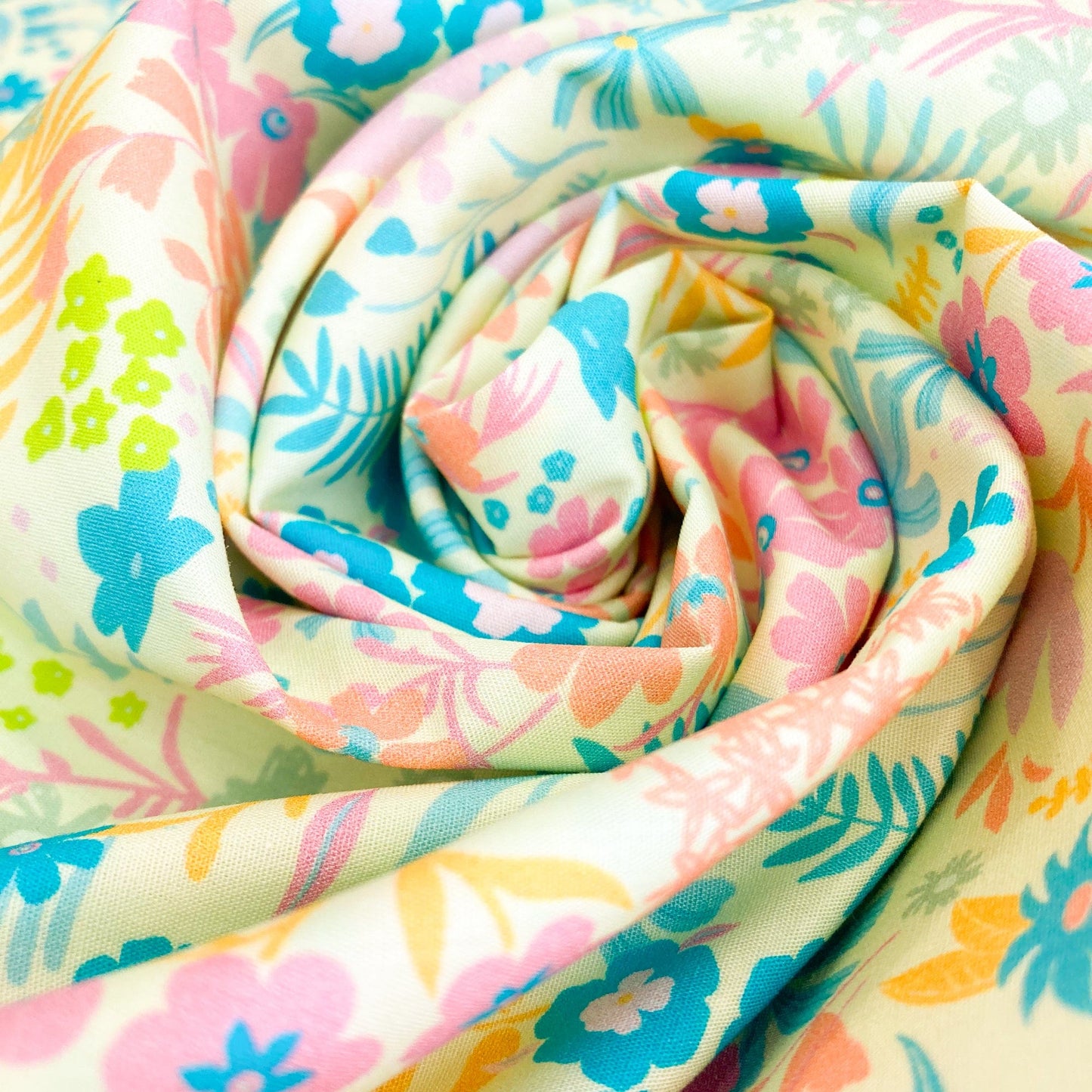 Swirl of colourful floral quilting cotton by Art Gallery Fabrics with pink, blue, green, and yellow flowers on a yellow background