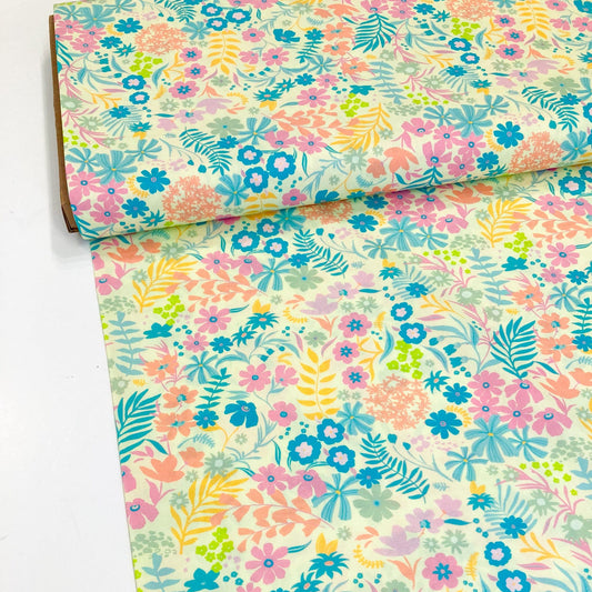 Bolt of colourful floral quilting cotton by Art Gallery Fabrics with pink, blue, green, and yellow flowers on a yellow background