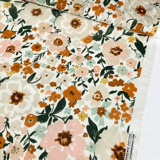 Floral organic cotton batiste in warm colours against a white background.