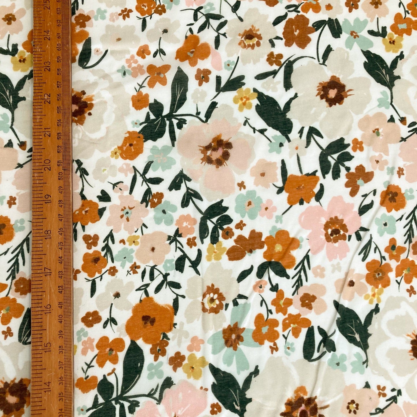 Floral organic batiste fabric shown with a ruler for scale