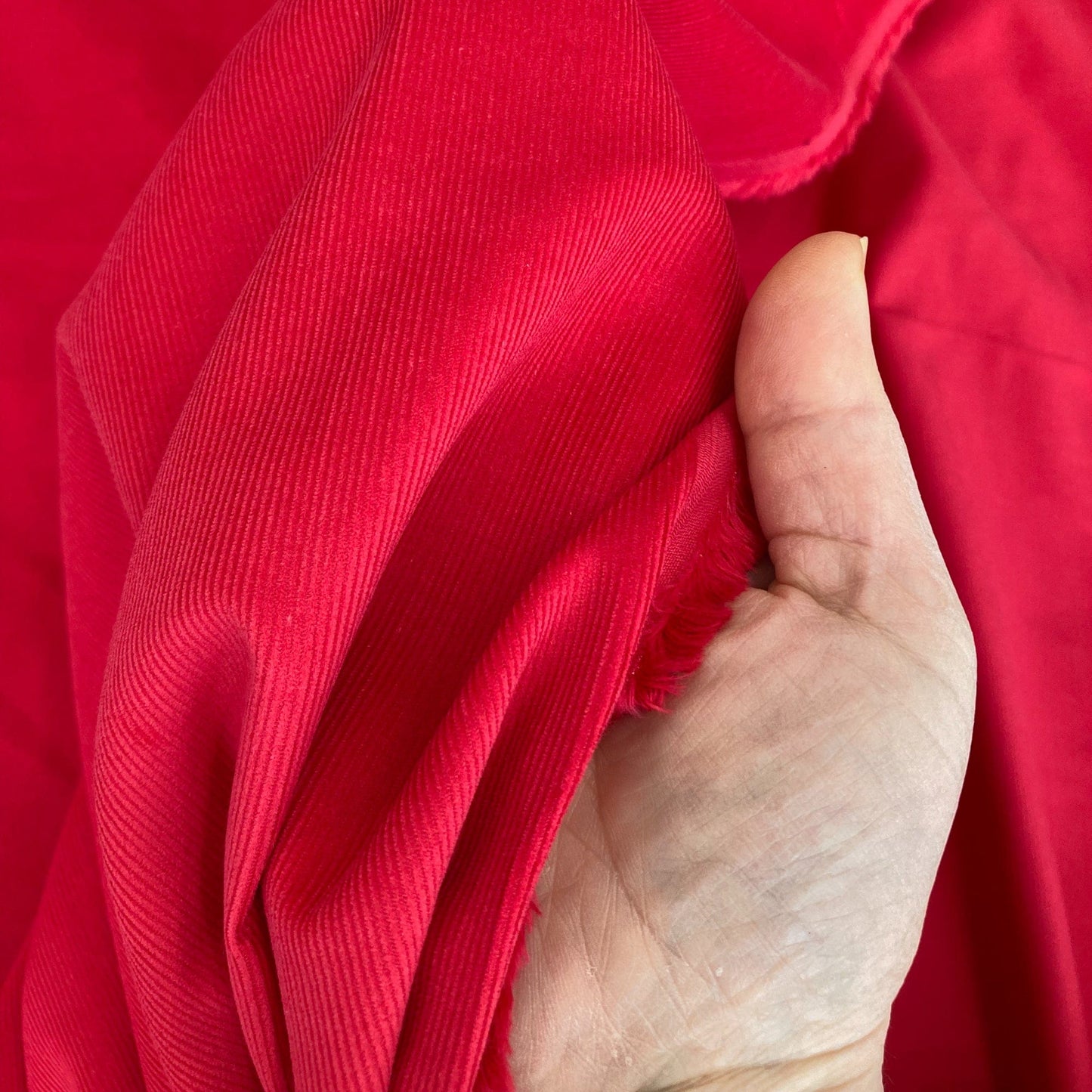 Hand holding red needlecord fabric