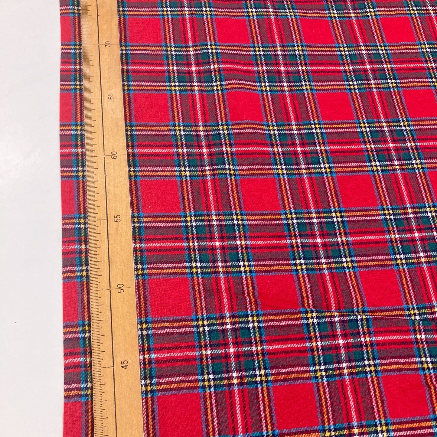 Red tartan brushed cotton fabric with a ruler for scale on a white background