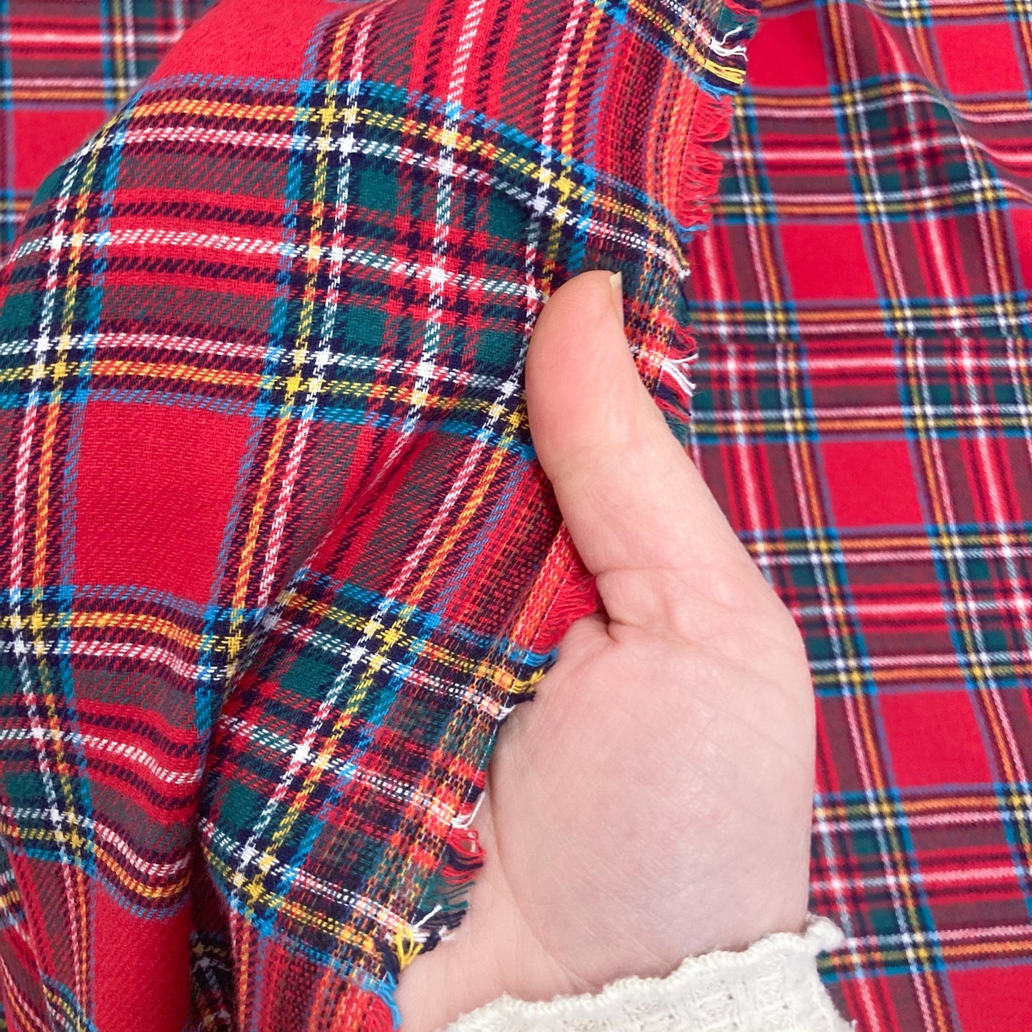 Hand holding red tartan brushed cotton fabric with a close-up view