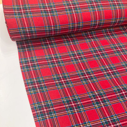 Roll of red tartan brushed cotton fabric on a white background
