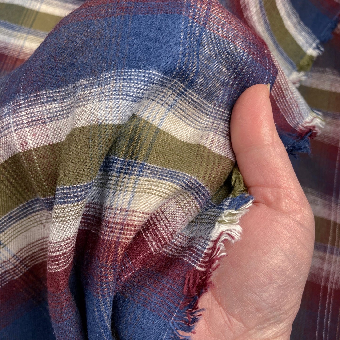 Close-up of flannel check fabric with a hand holding it