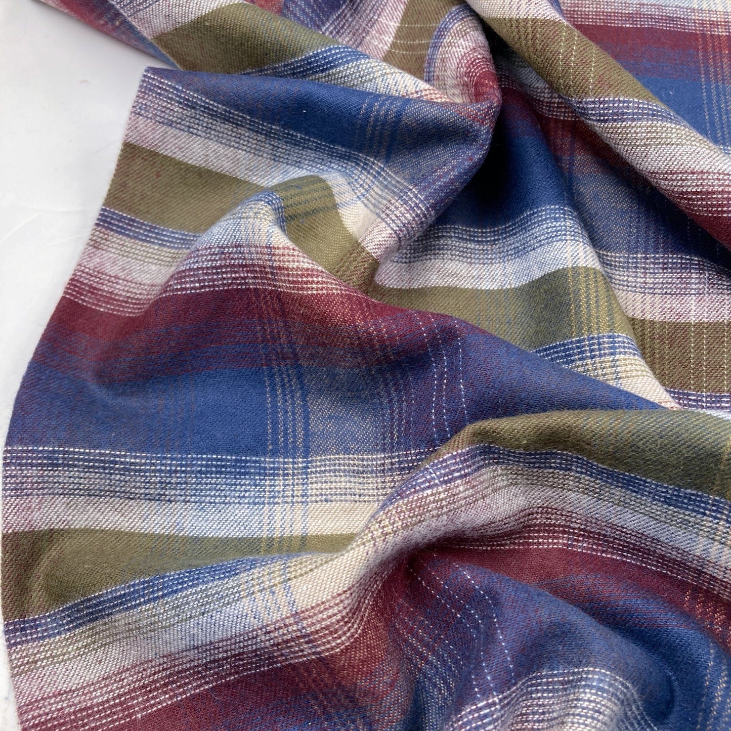 Close-up of plaid flannel fabric with blue, green, and red colors on a white background