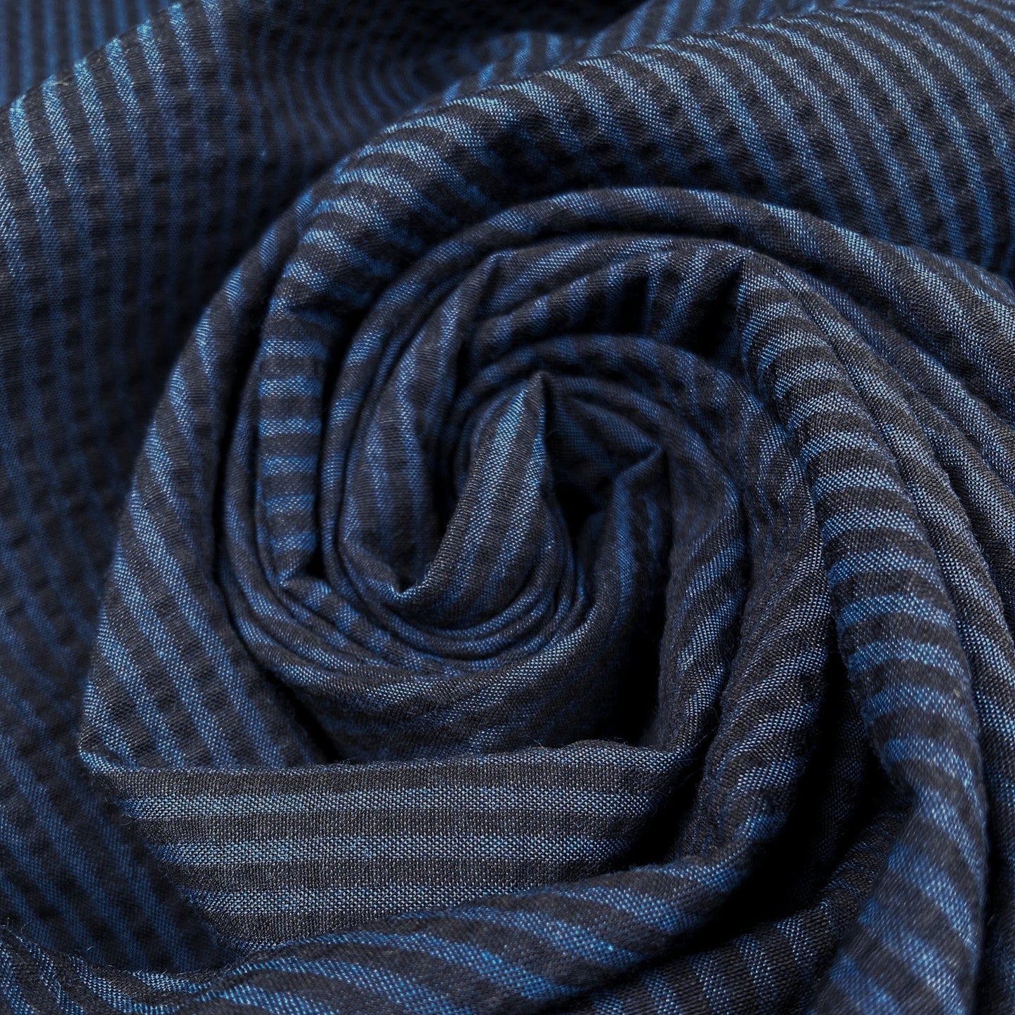 Close-up of a rswirl of cotton seersucker fabric with a blue stripe
