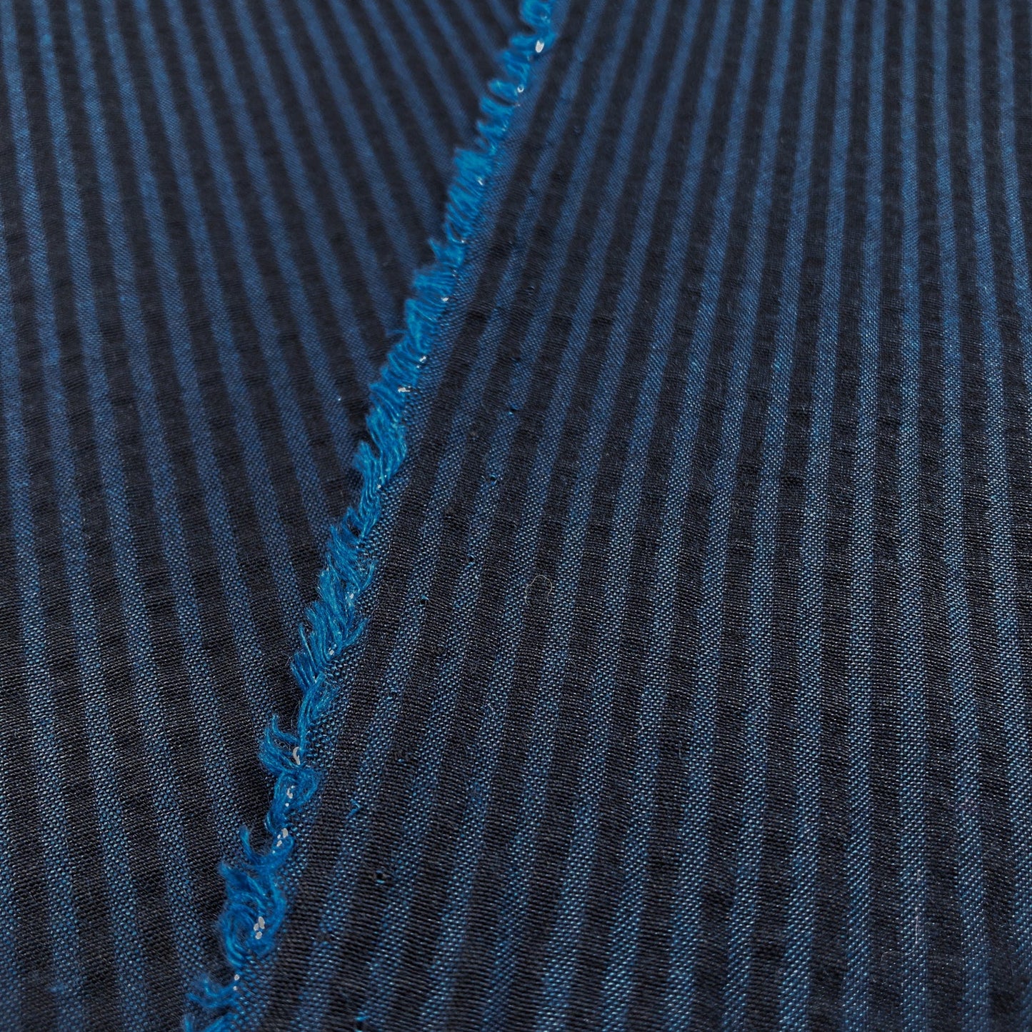 Close-up of blue striped cotton seersucker fabric showing front and back
