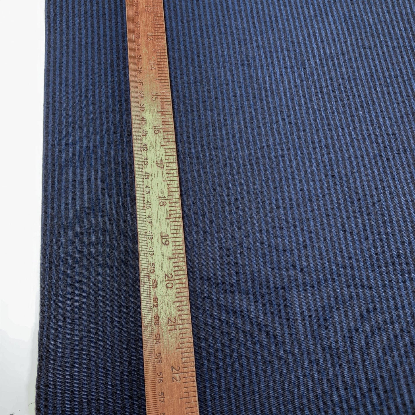 Blue striped cotton seersucker fabric with a wooden ruler for scale