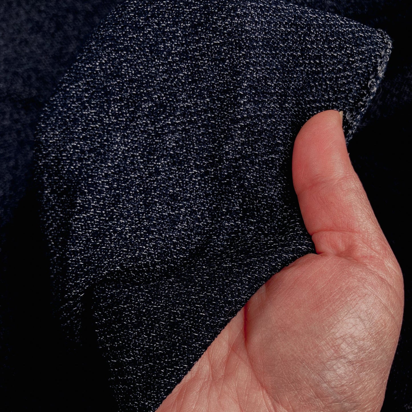 Hand holding a length of dark blue textured fabric