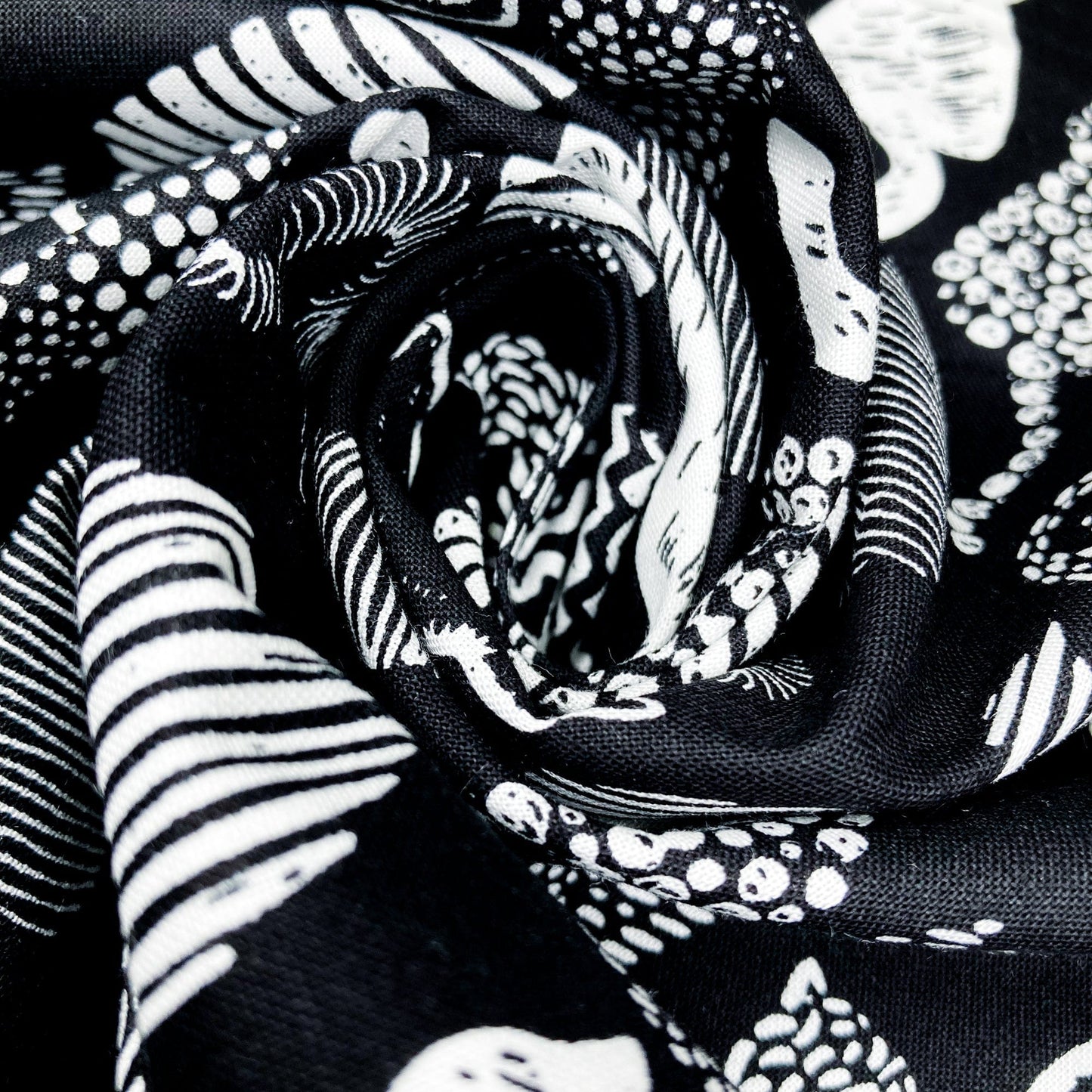 A swirl of cotton fabric with a graphic style cat print in black and white.