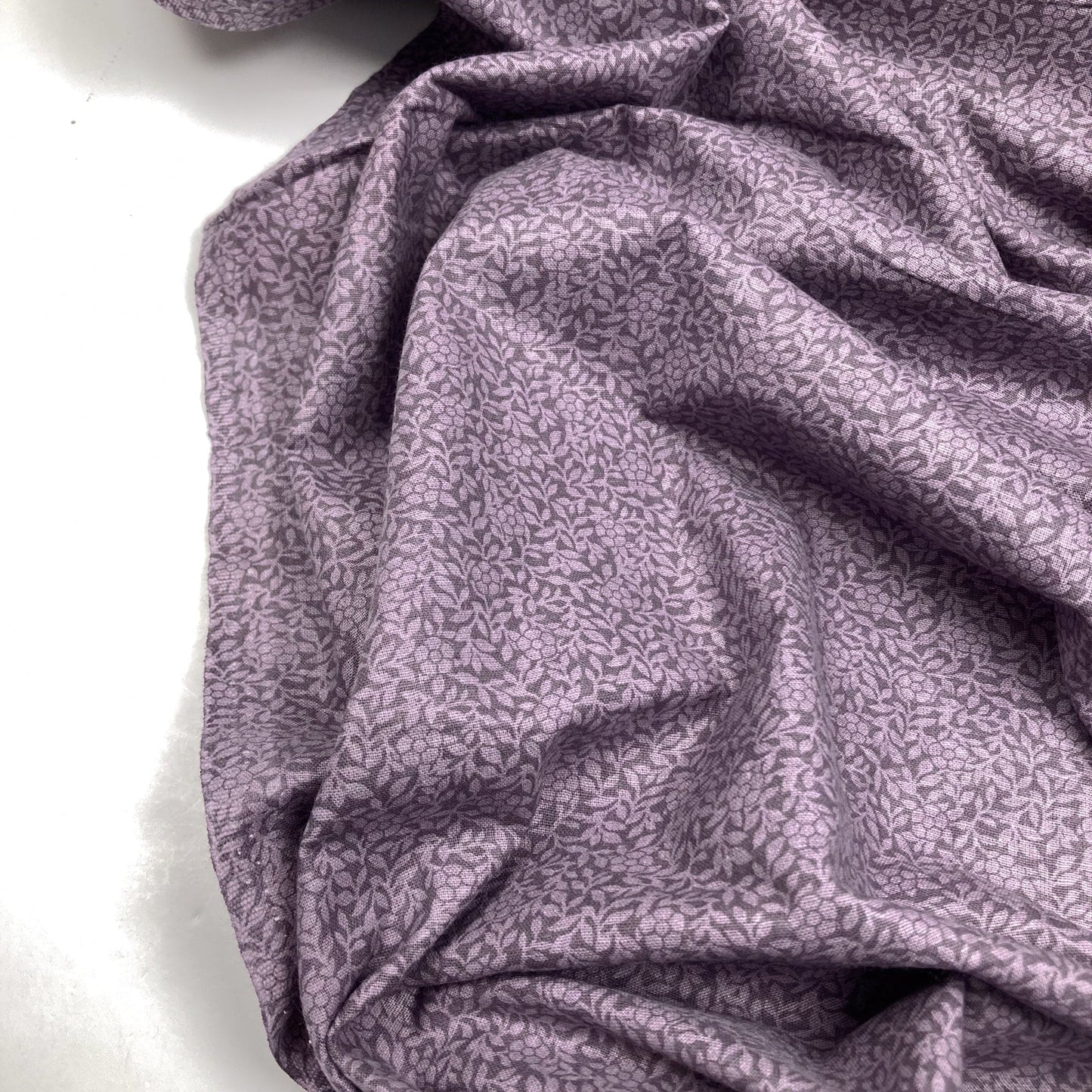 Purple cotton quiltback fabric with a small floral pattern on a white background
