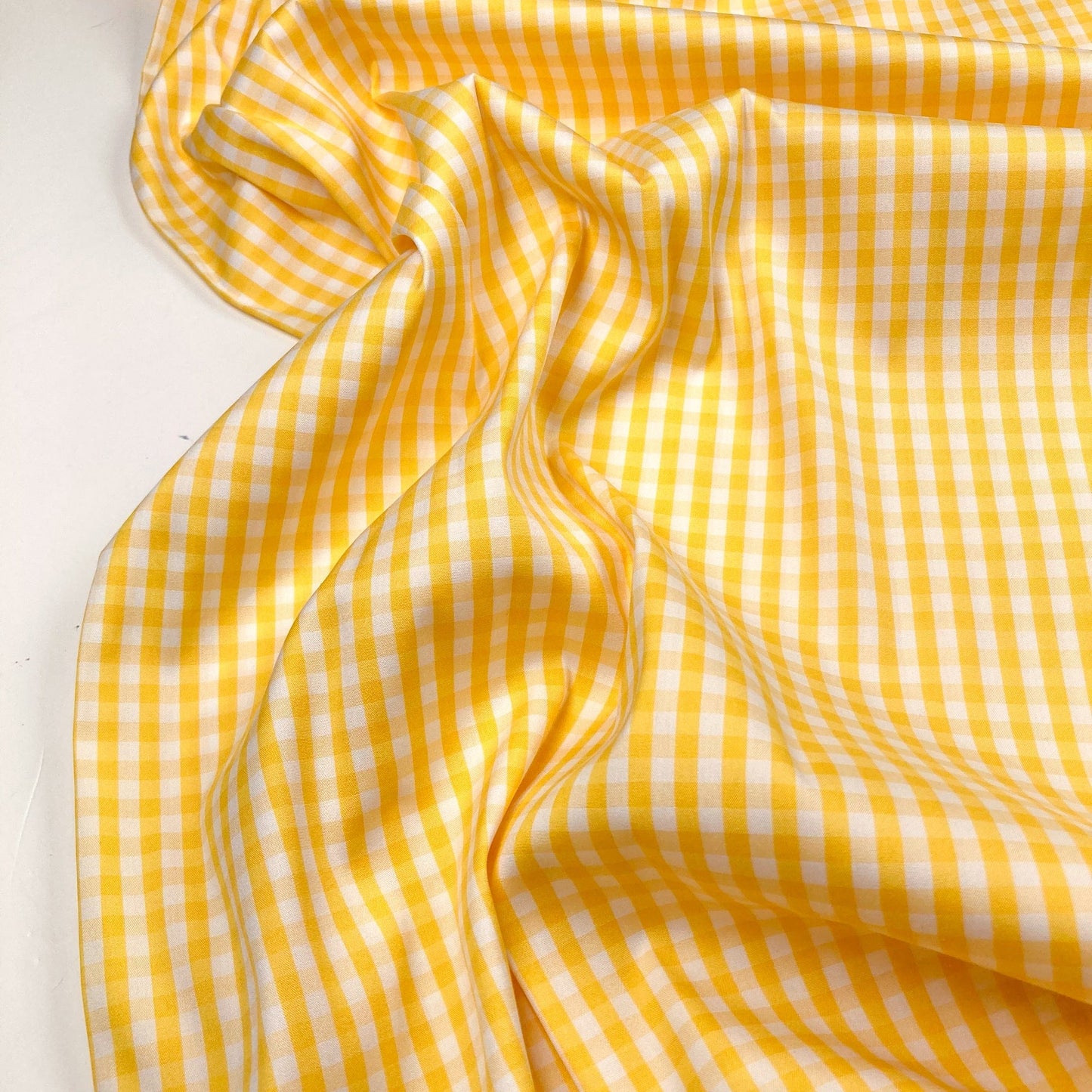 Yellow and white gingham fabric arranged on a white background