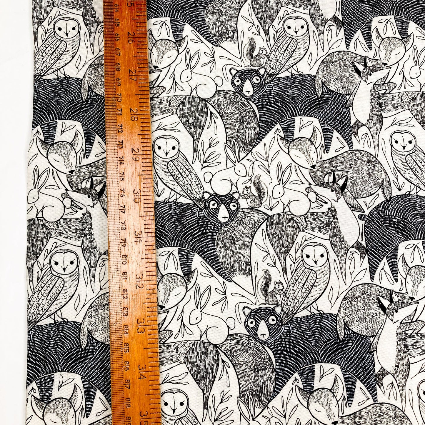 Fabric with black and white forest animals with a ruler for scale.