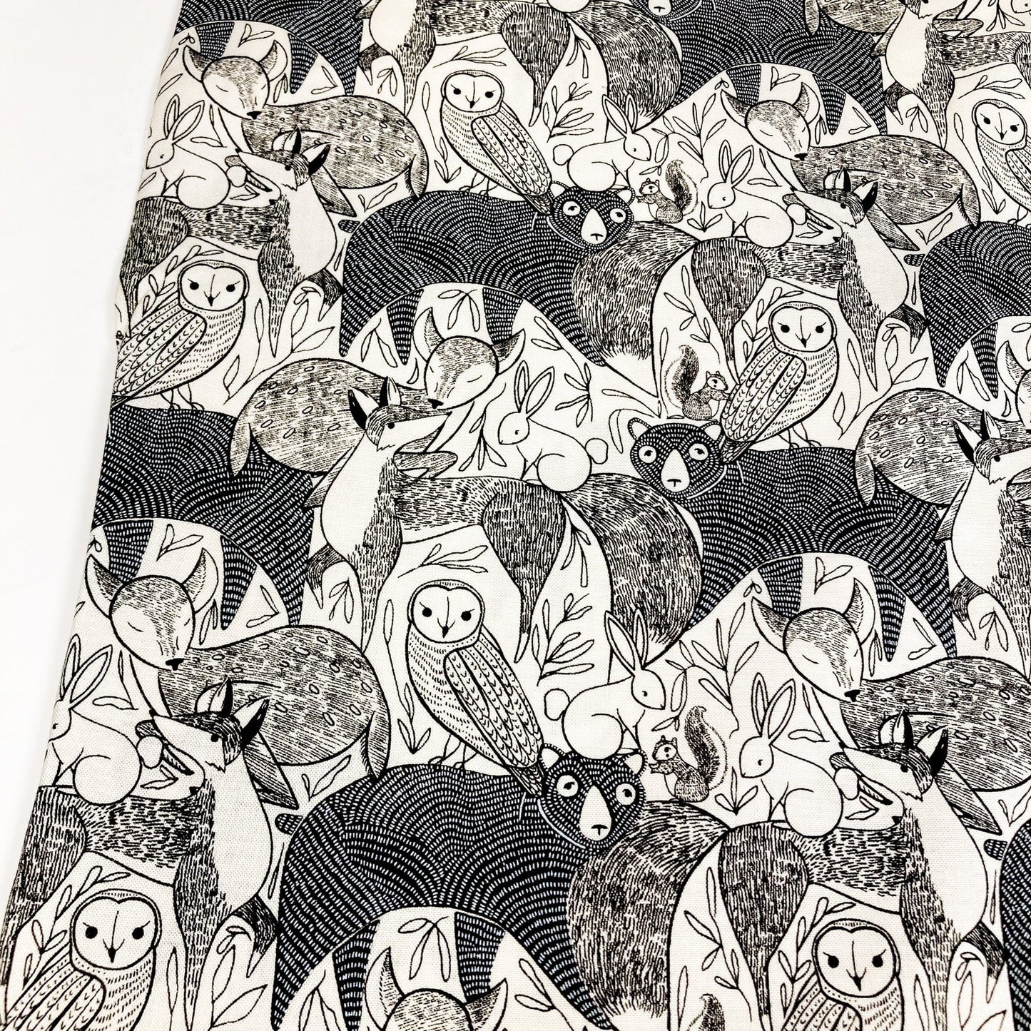 Quilting cotton with a black and white pattern of various forest animals on a white background