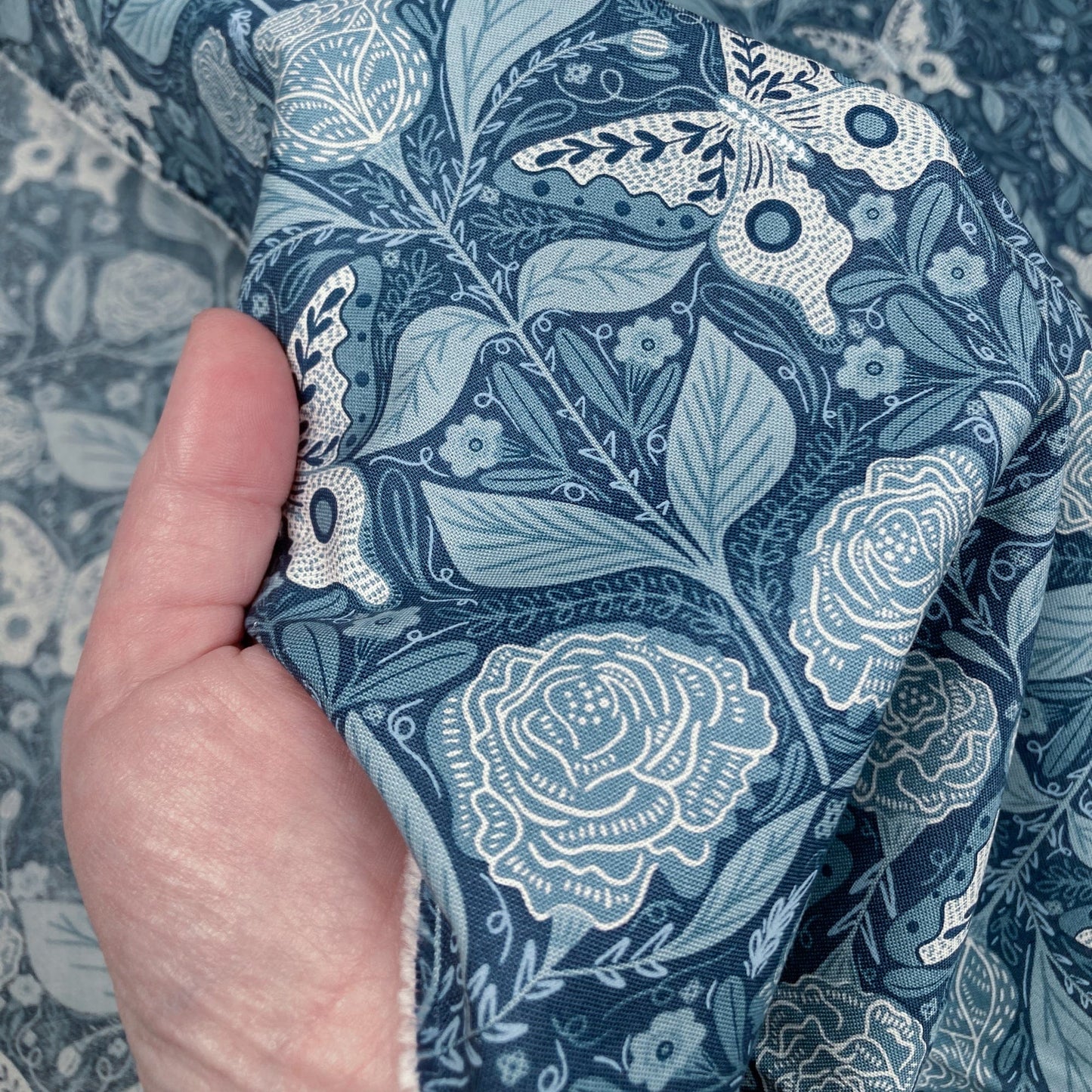 Hand holding blue floral quilting cotton