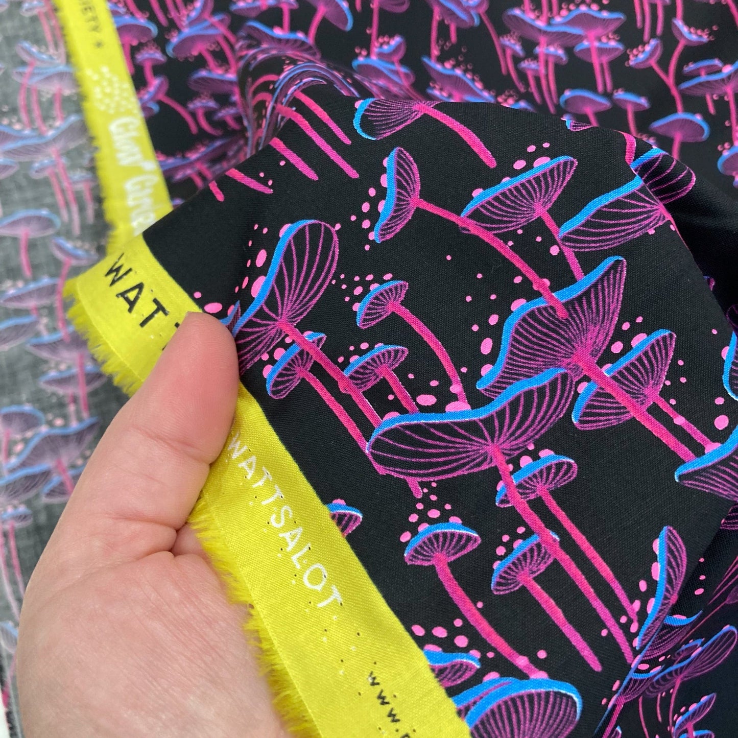 Neon mushroom patterned fabric held by a hand for scale.