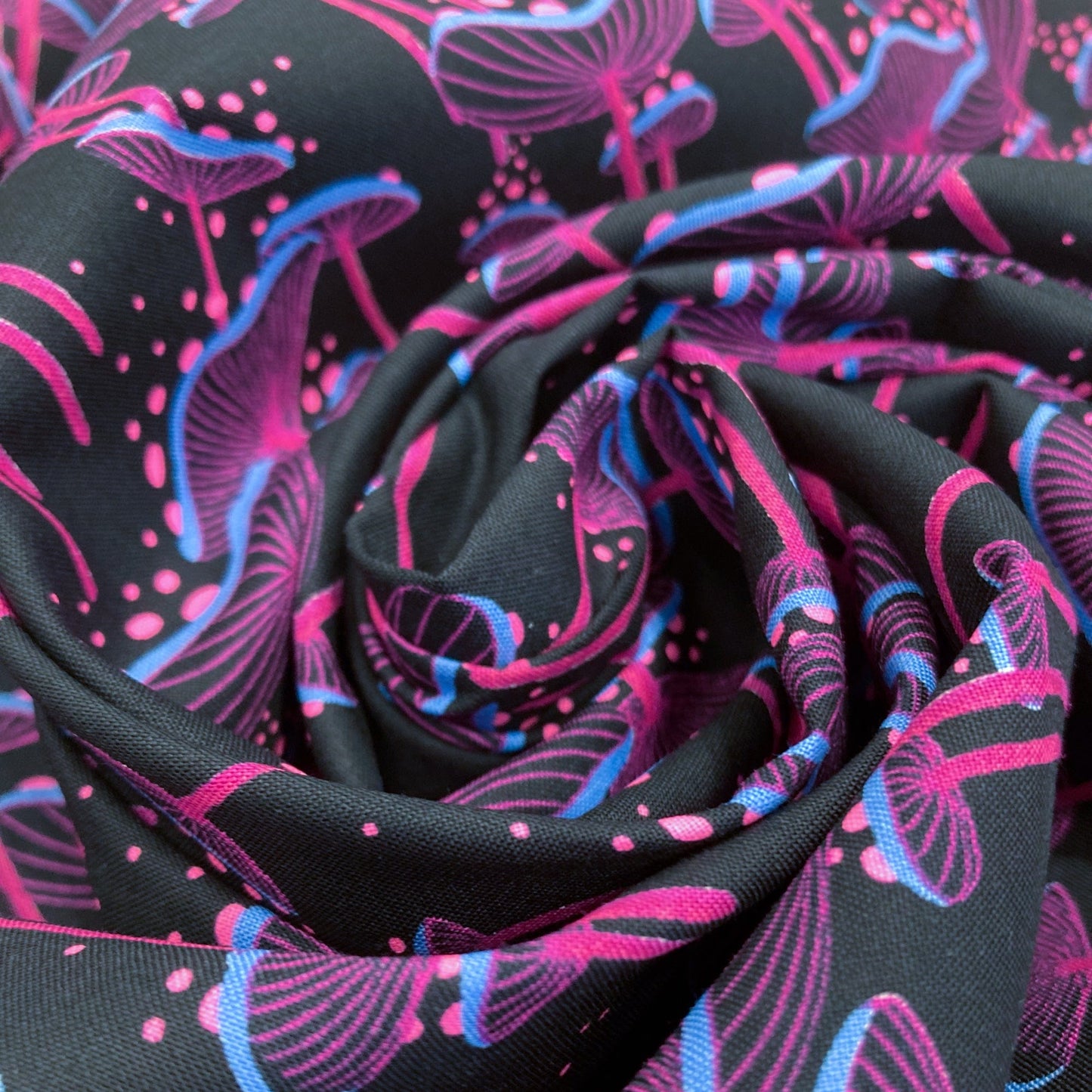 Close-up of black fabric with neon pink and blue mushroom print.