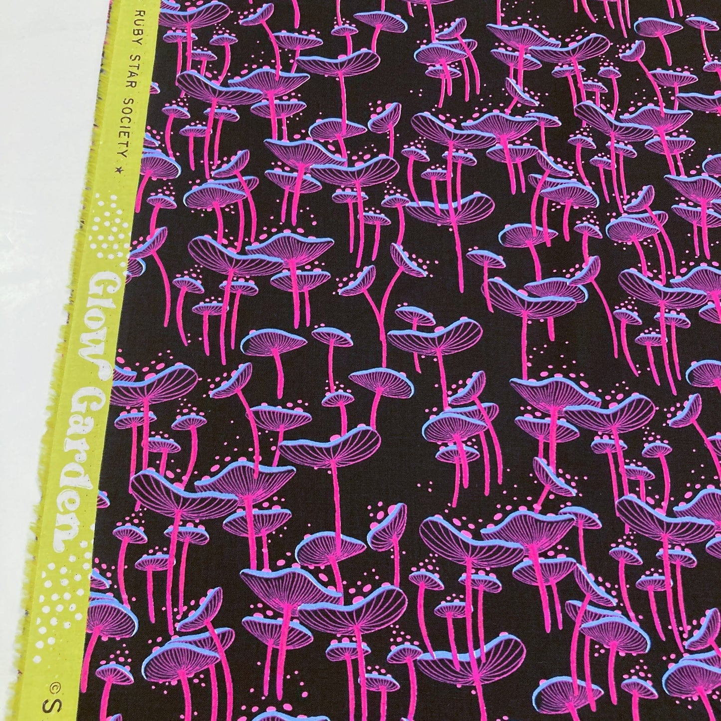 Fabric with pink and purple mushroom pattern on a black background.
