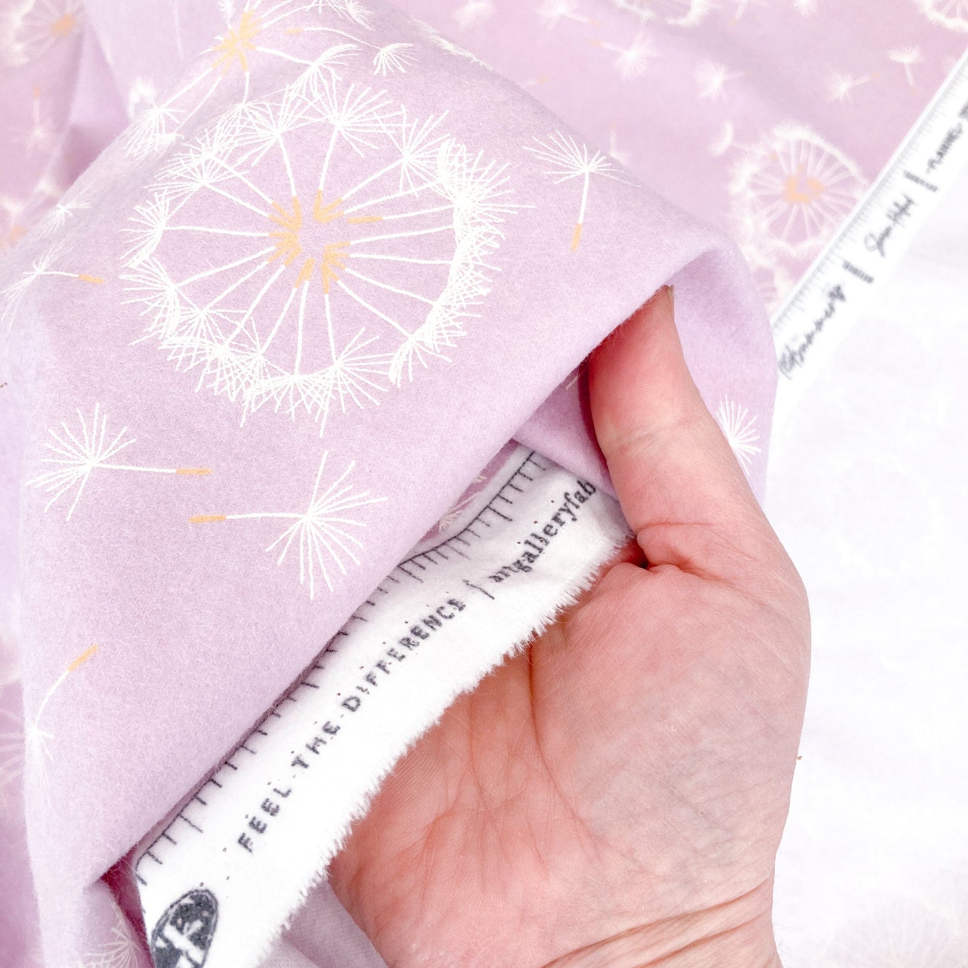 Hand holding Lilac brushed cotton fabric with dandelion pattern