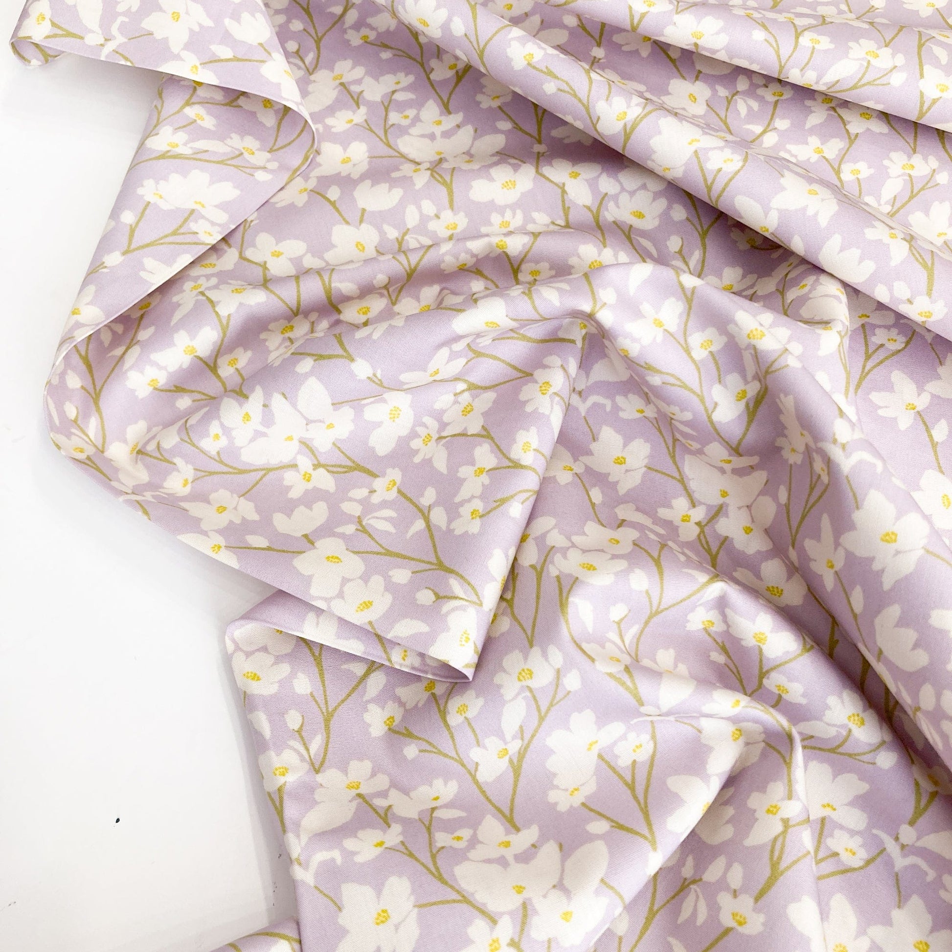 Floral cotton fabric with cream flowers on a lilac background.