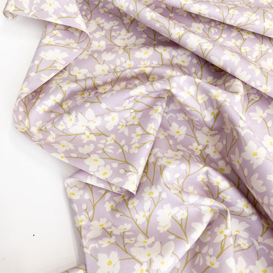 Floral cotton fabric with cream flowers on a lilac background.