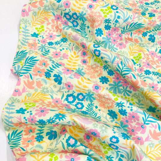 Colorful floral quilting cotton by Art Gallery Fabrics with pink, blue, green, and yellow flowers on a yellow background