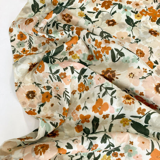 Floral organic cotton batiste with burnt orange, green, and pink flowers on a cream background.