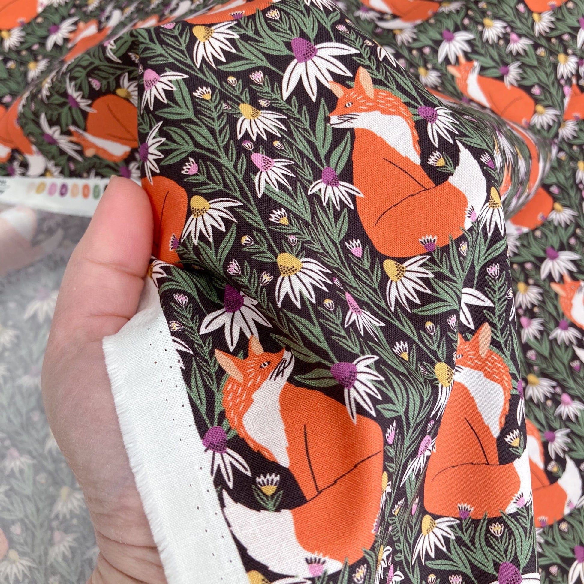 Organic quilting cotton with fox and floral pattern. held by a hand