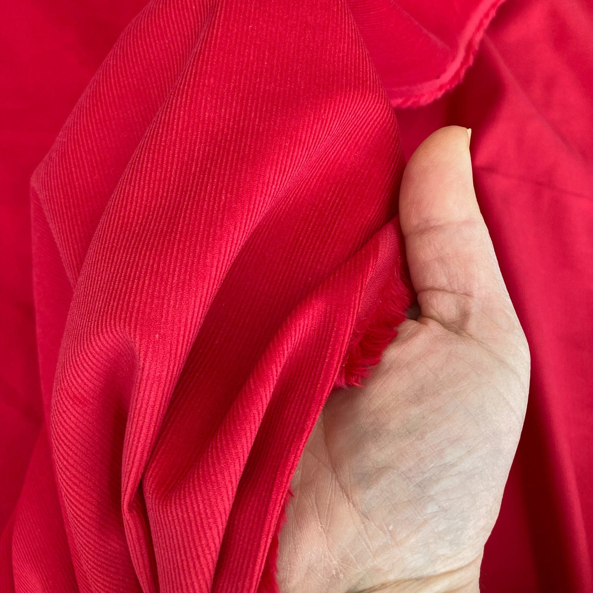 Hand holding red needlecord fabric 