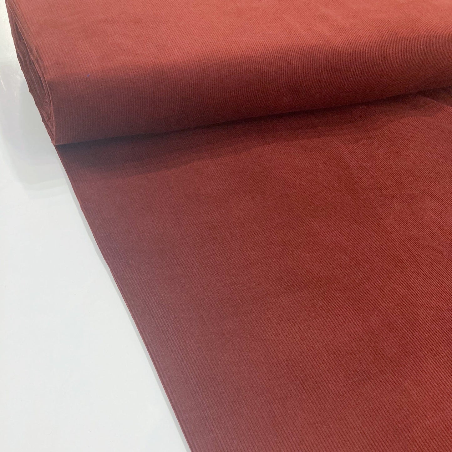 Bolt of brown corduroy fabric on a white background