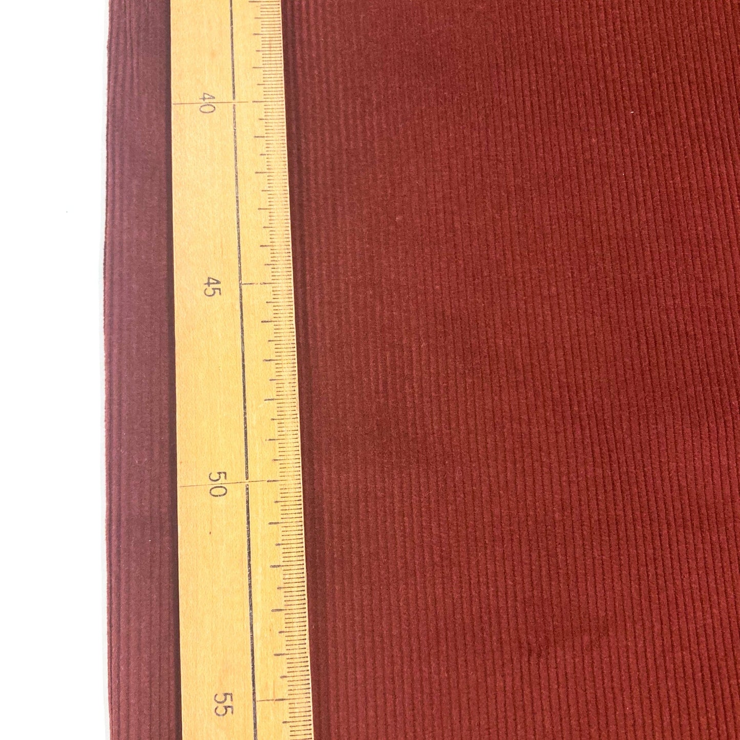Brown corduroy fabric with a wooden ruler for scale 