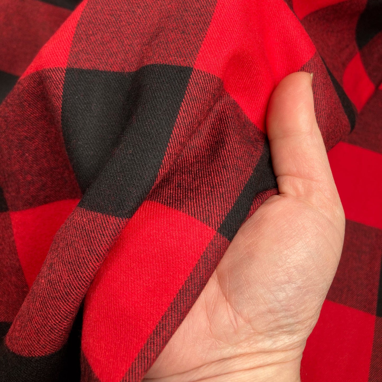Hand holding red and black buffalo check flannel twill fabric