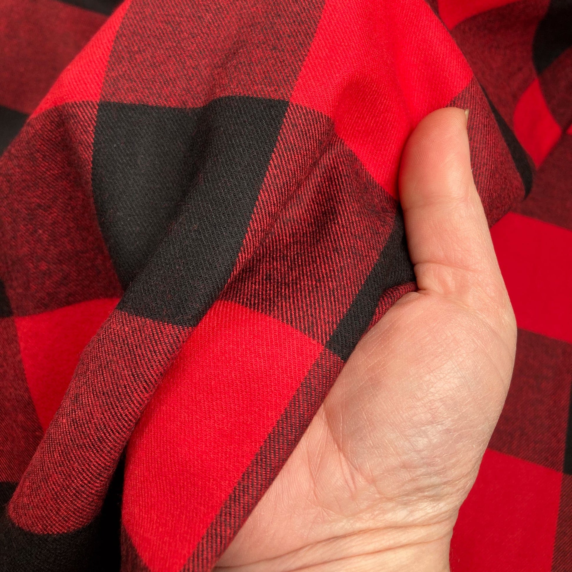 Hand holding red and black buffalo check flannel twill fabric