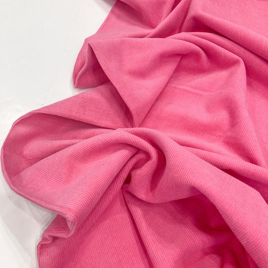 Close-up of bright pink cotton corduroy fabric on a white background