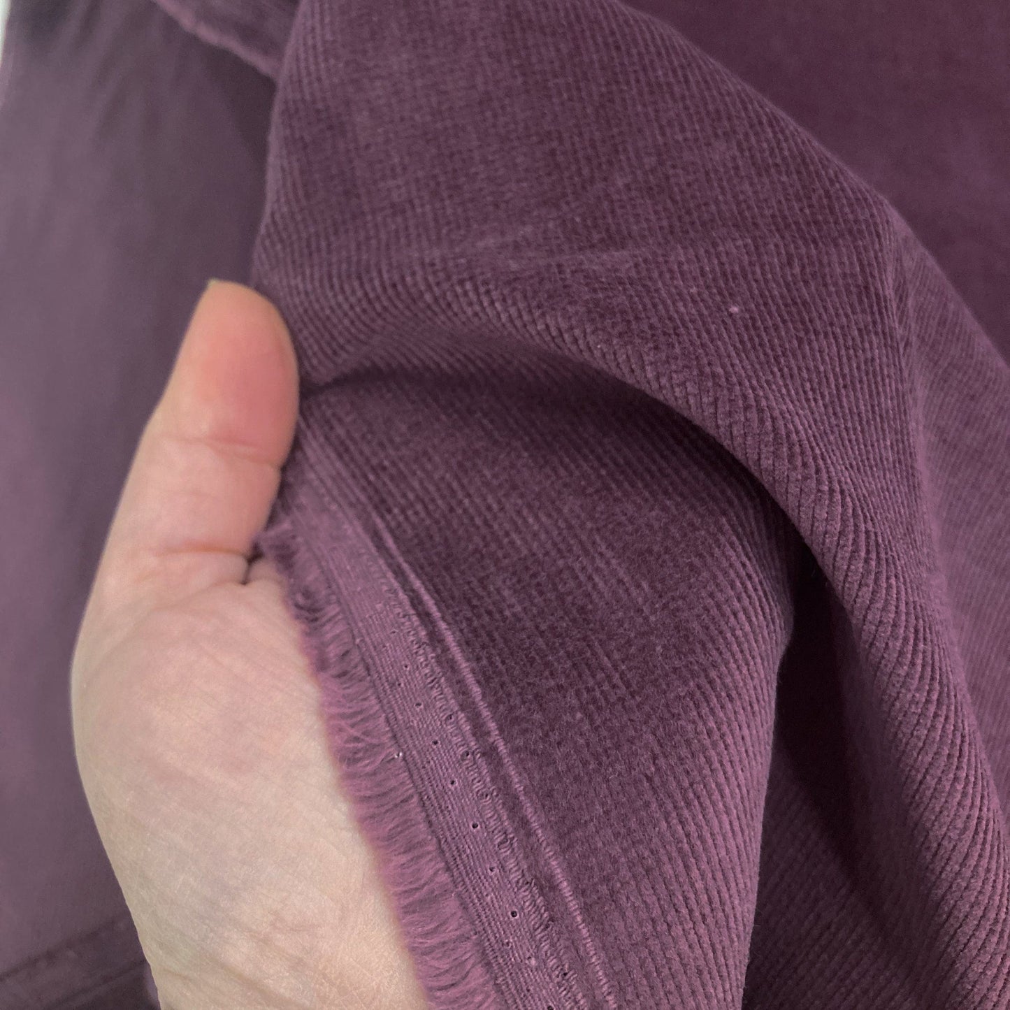 Close-up of a hand holding purple corduroy fabric