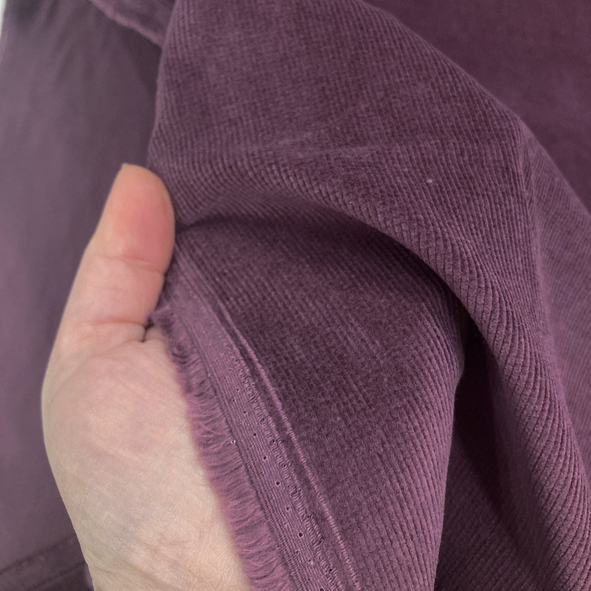 Close-up of a hand holding purple corduroy fabric