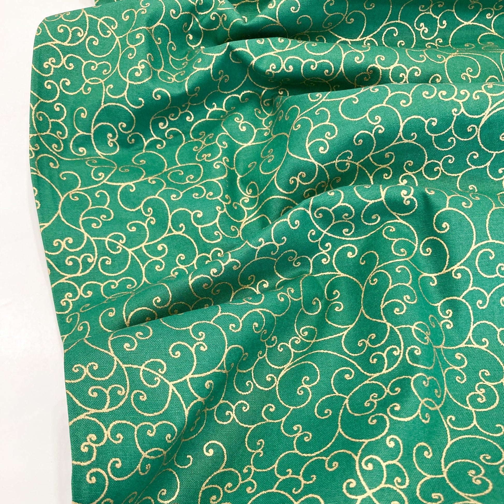 Green quilting cotton with celtic style metallic gold swirl pattern