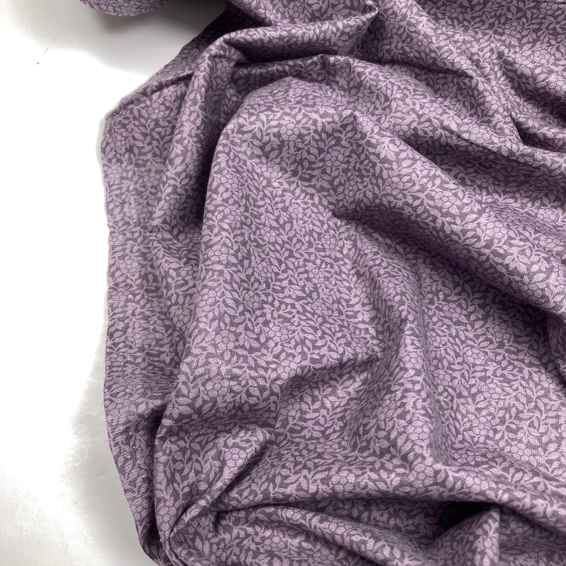 Purple cotton quiltback fabric with a small floral pattern on a white background