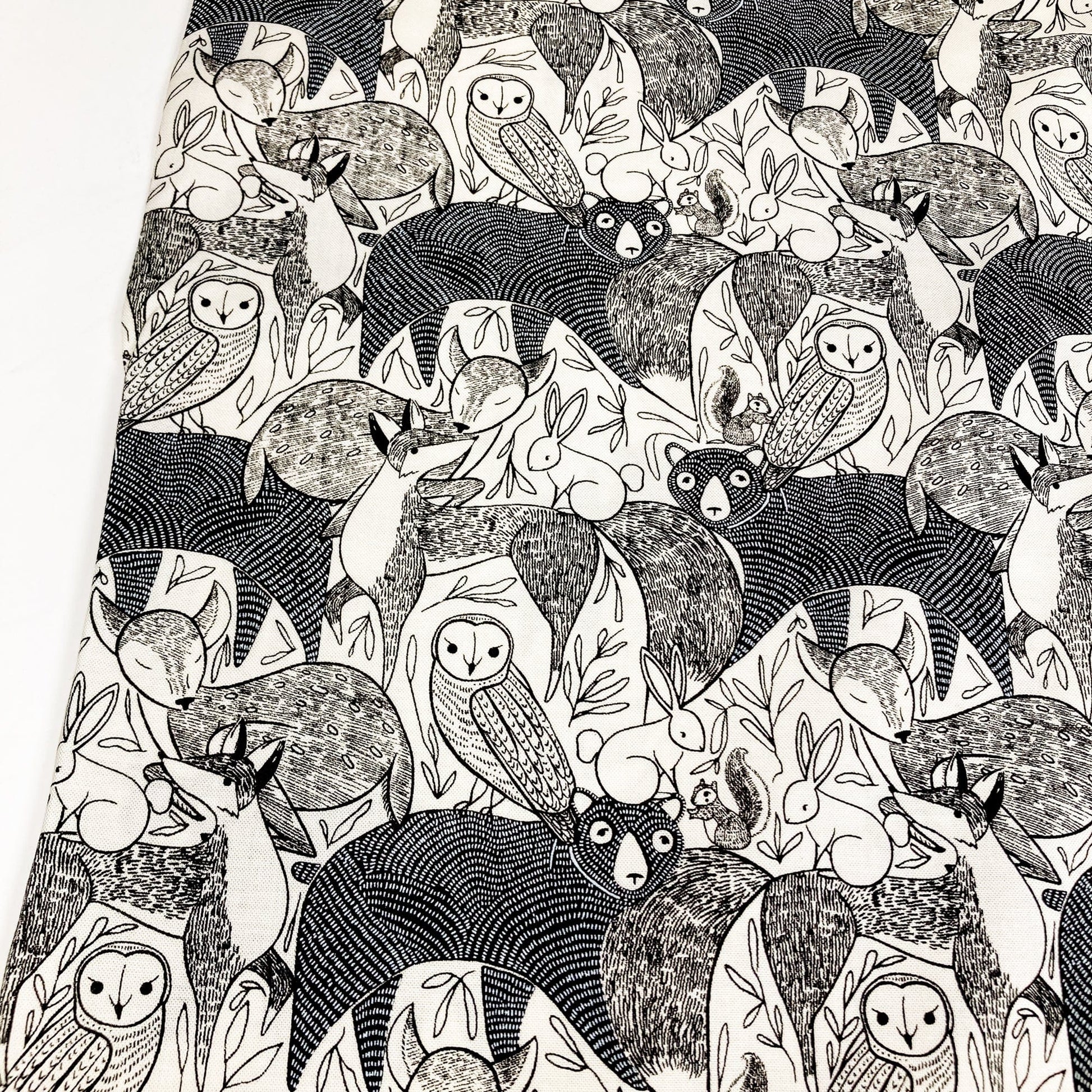 Quilting cotton with a black and white pattern of various forest animals on a white background