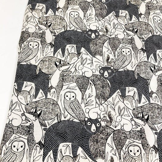 Quilting cotton with a black and white pattern of various forest animals on a white background