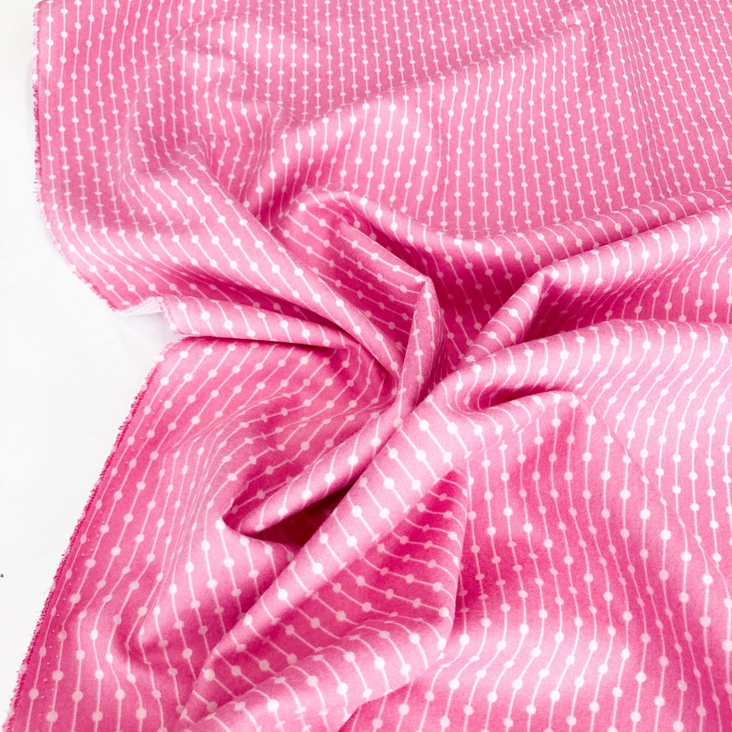Pink fabric with white polka dots on a white background