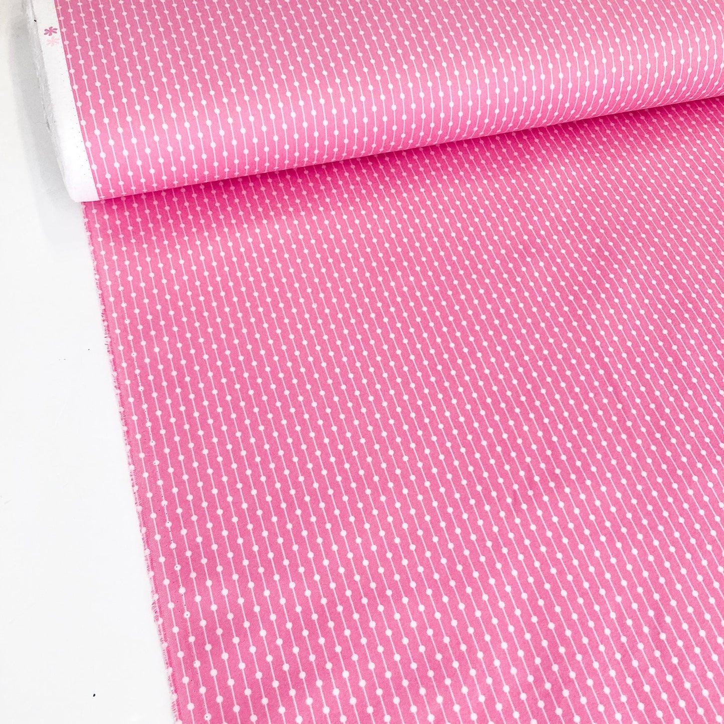 Roll of pink fabric with a subtle pattern on a white background