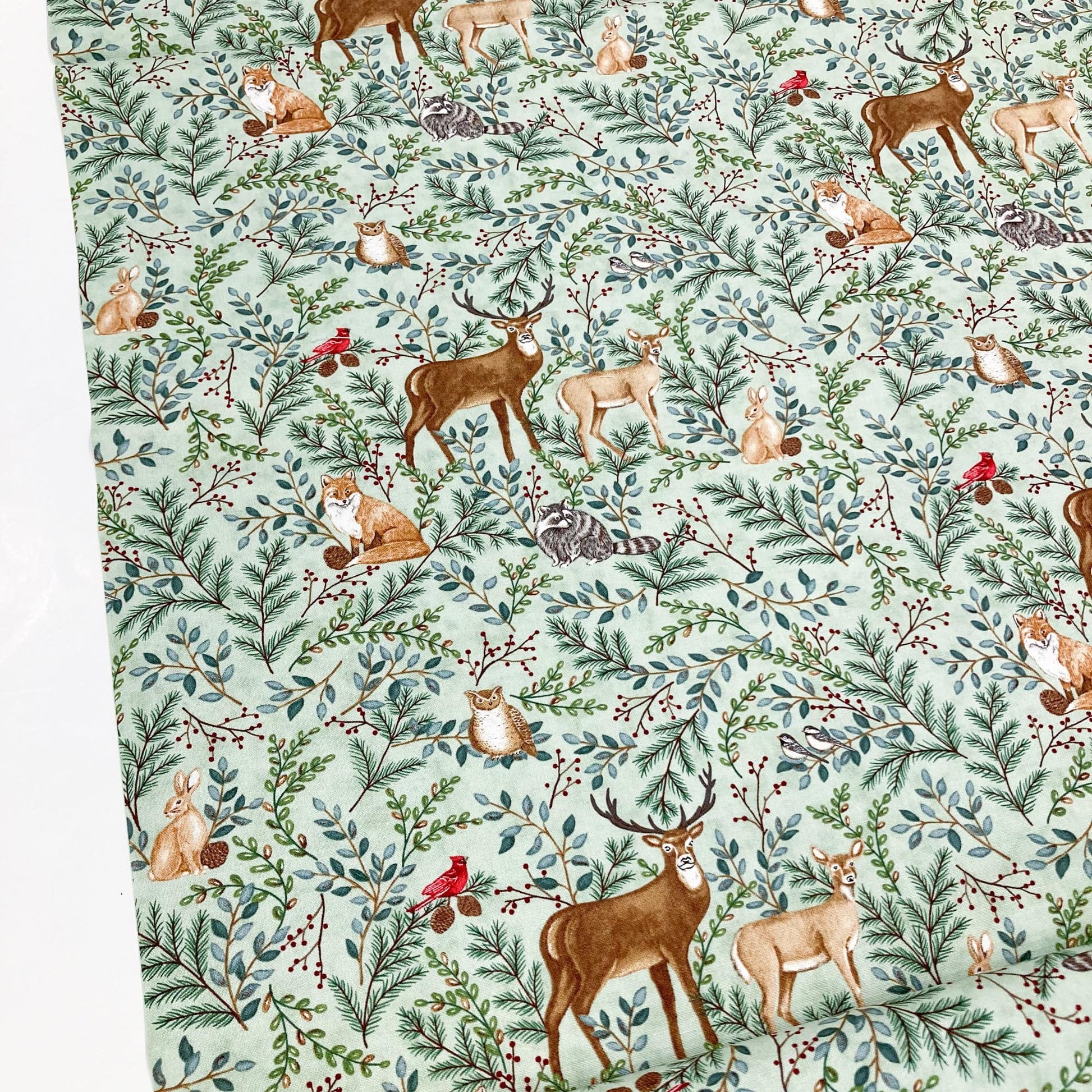 Quilting cotton with deer, foxes, and other forest animals on a green background