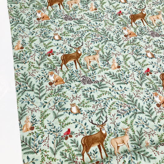 Quilting cotton with deer, foxes, and other forest animals on a green background