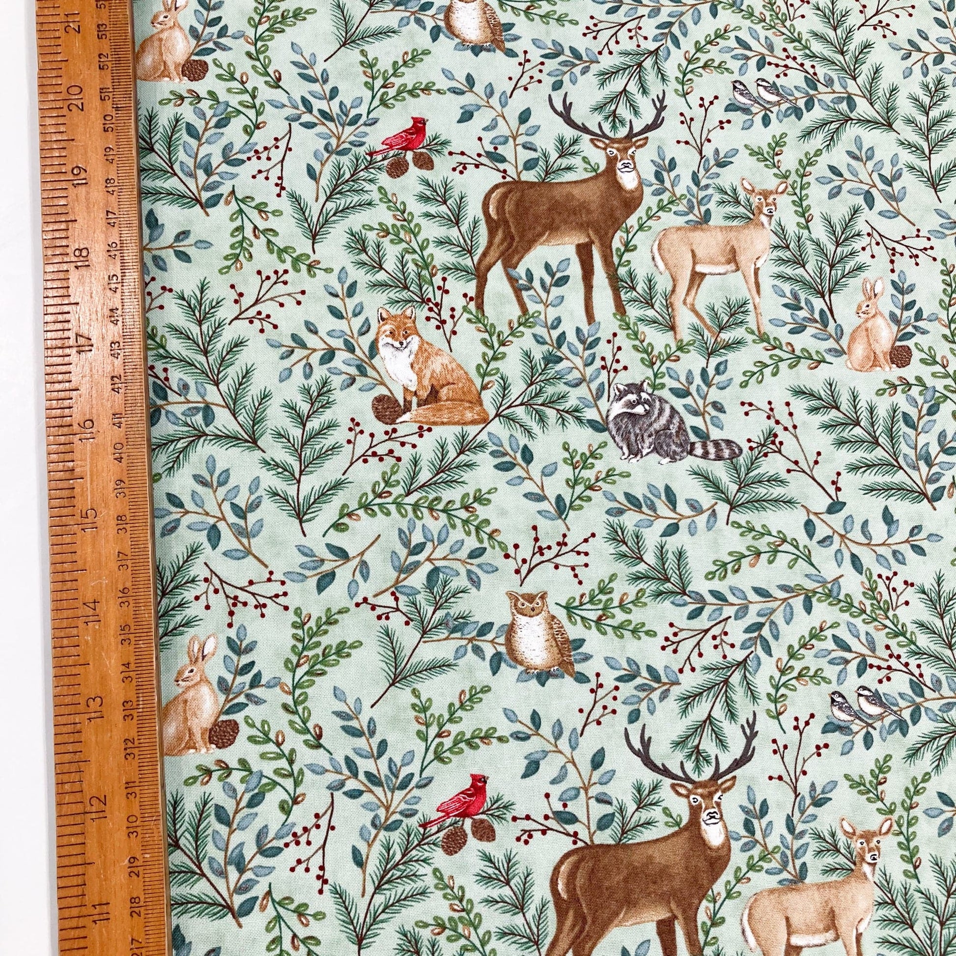 Woodland animal printed quilting cotton with deer, fox, and birds, with a ruler.